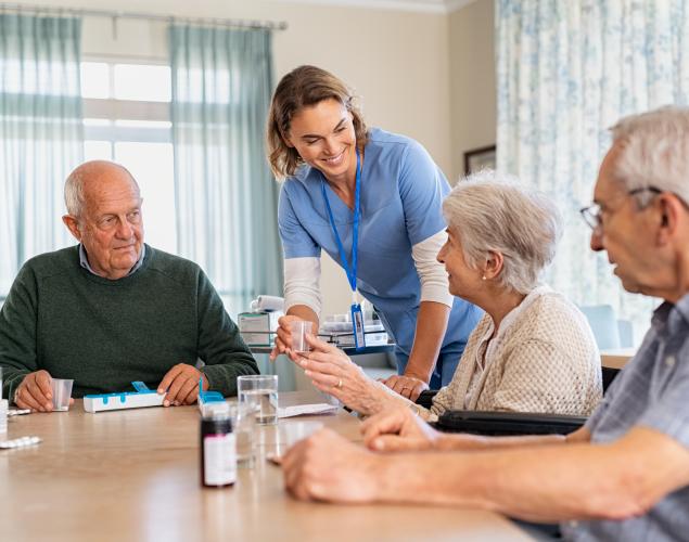 Lovely nurse giving medicine to senior woman at care facility.
