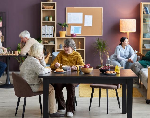 common room in retirement home with diverse group of seniors enjoying leisure activities