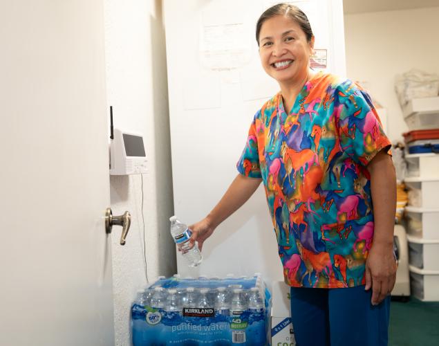 Caregiver smiling next to a case of water.