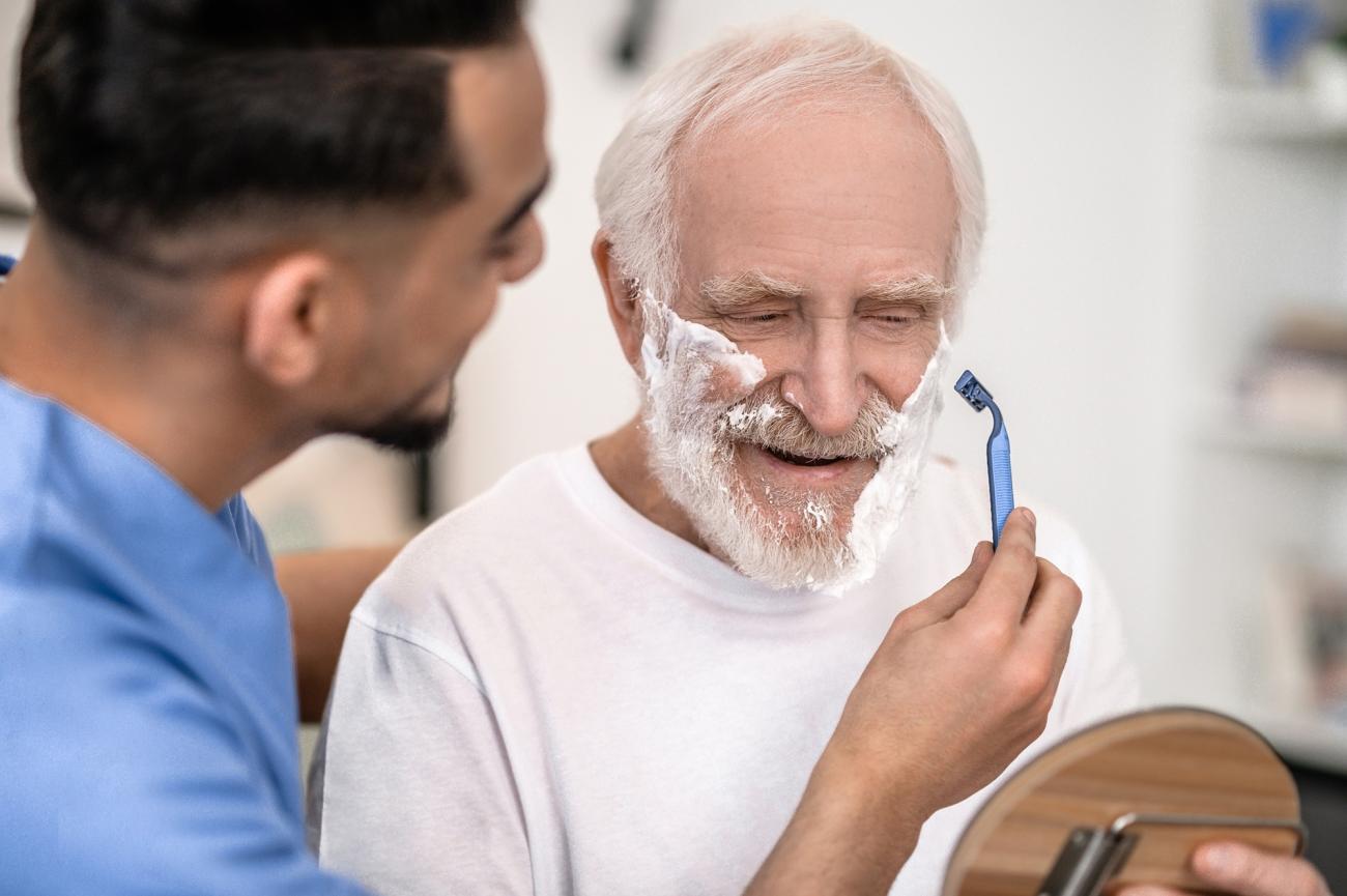 a home care aide helping a man shave