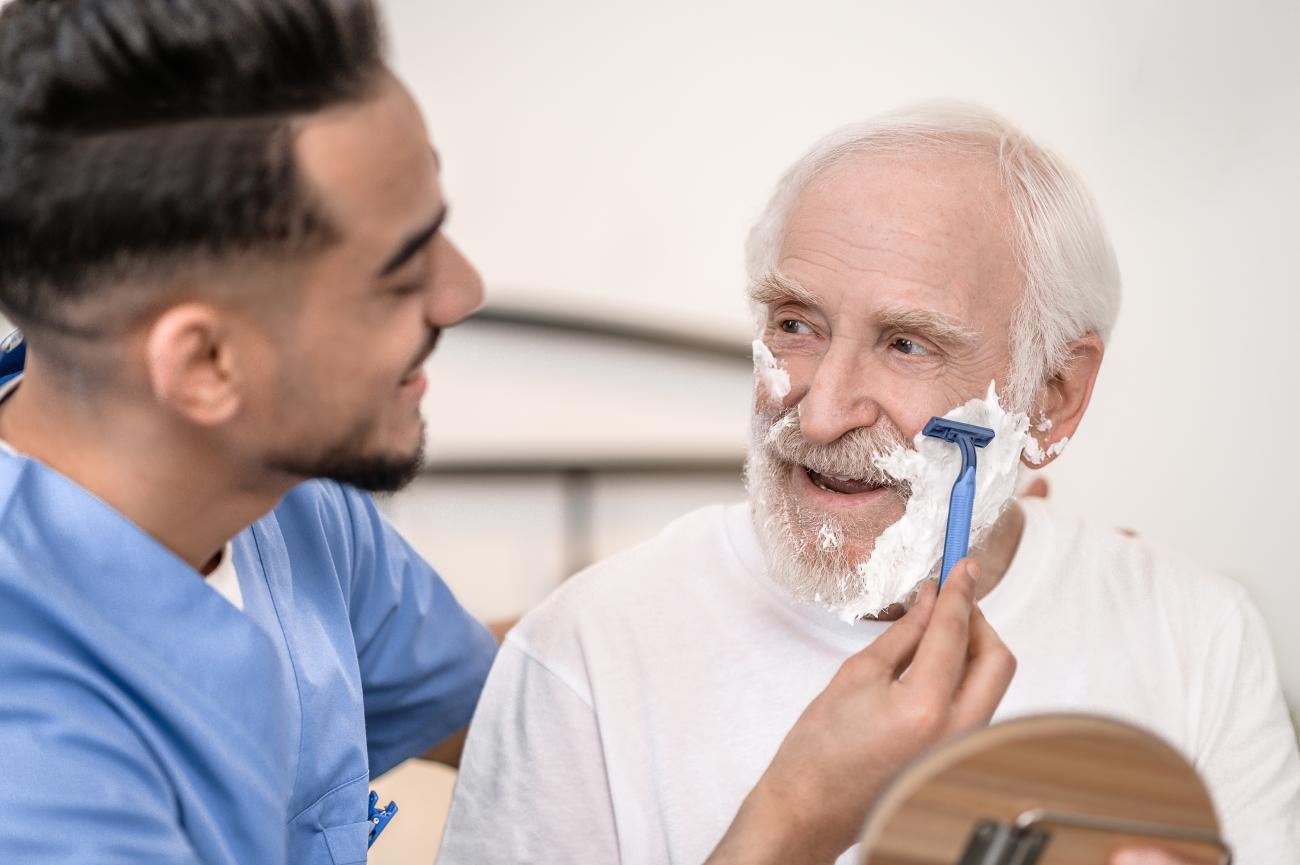 Caregiver shaving a senior man.