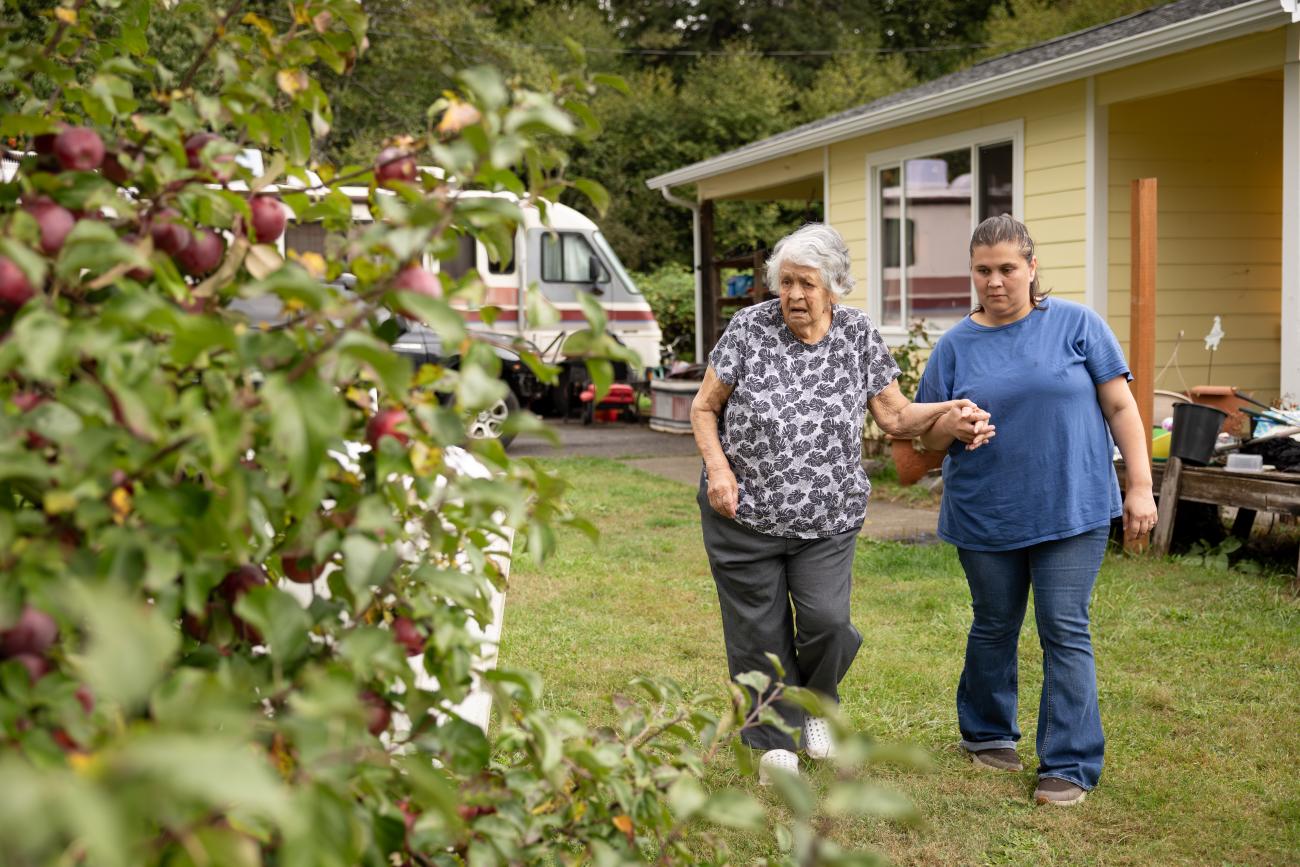 Caregiver walking while supporting client with holding hands.