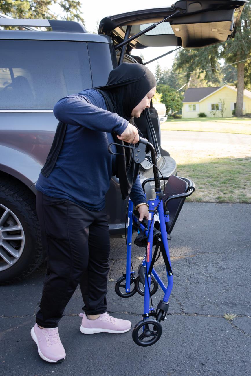 Caregiver getting walker out from the back of their van.