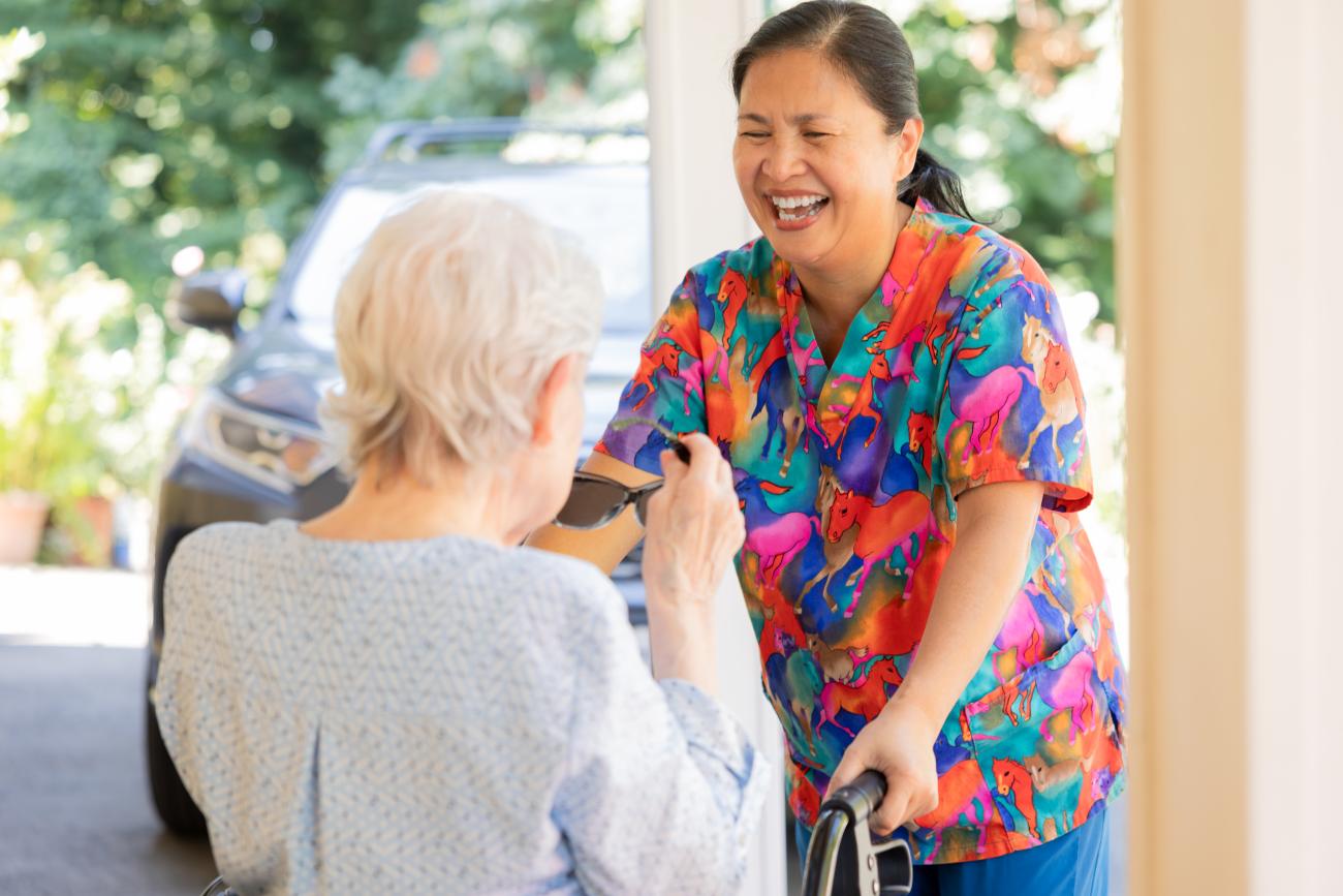Smiling caregiver standing with a senior women.