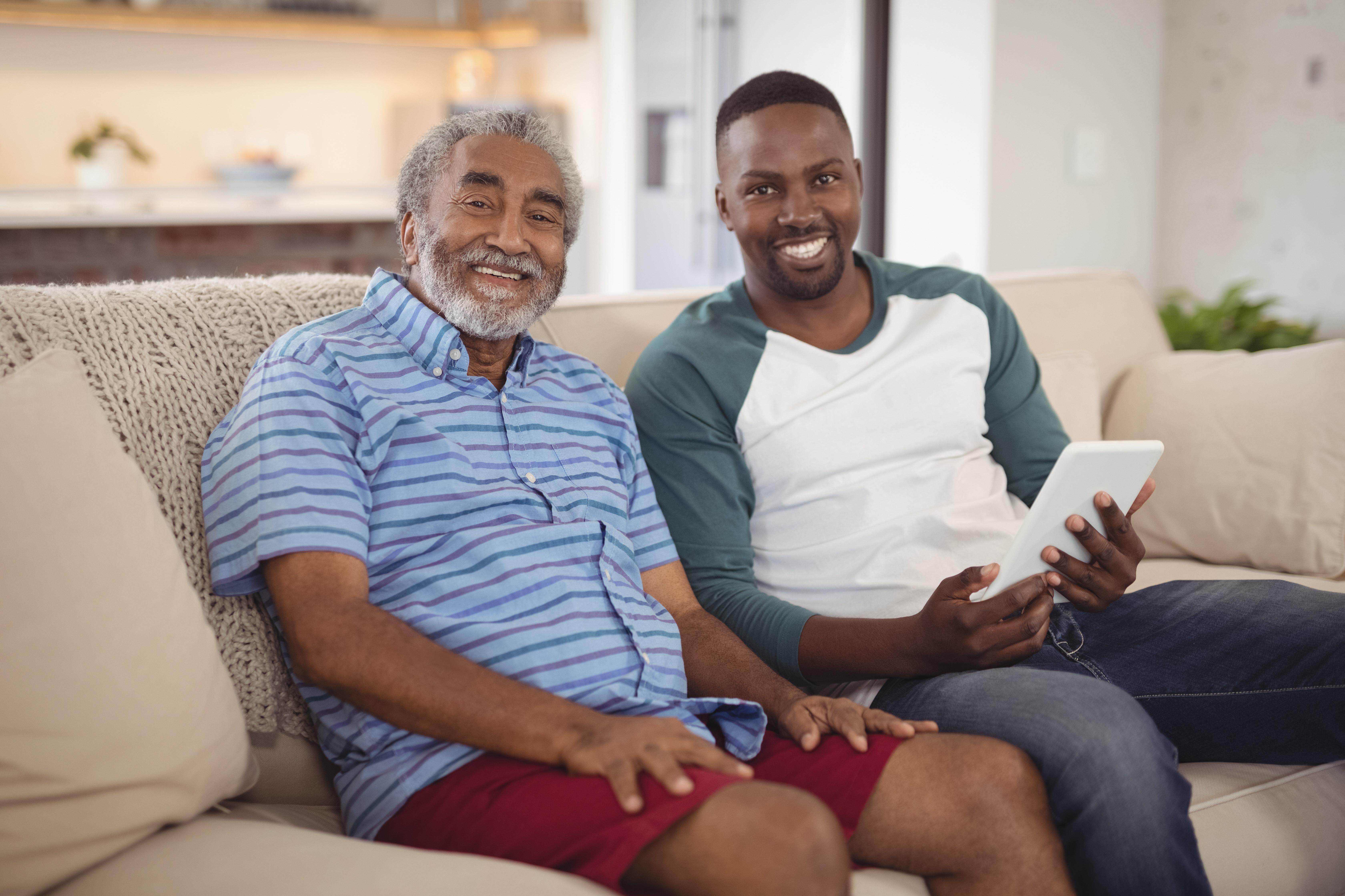 Two adults sitting on a couch smiling.