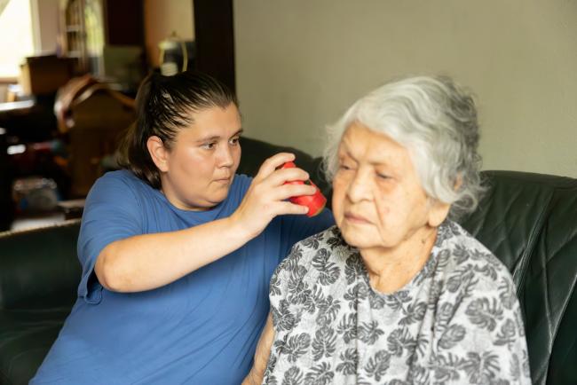 Caregiver using a blood glucose monitor on client.