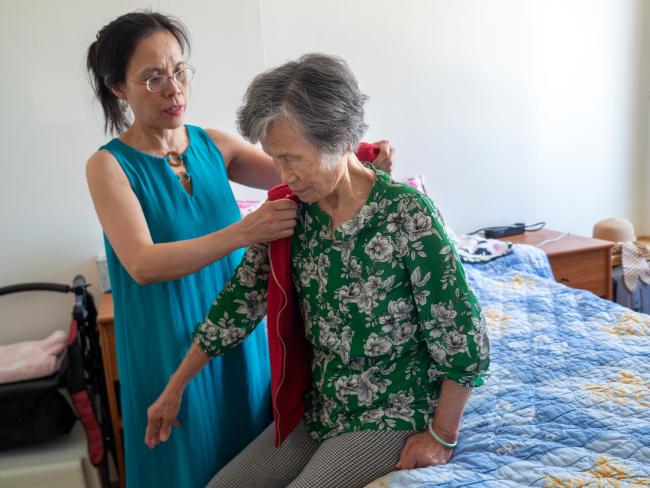 Family caregiver helping older adult get dressed.