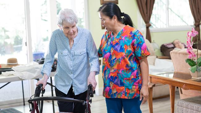 Caregiver helping support client with walker.