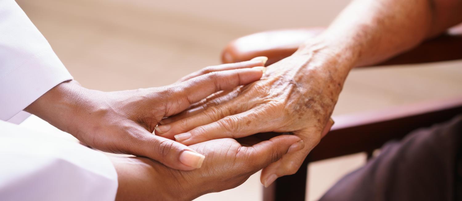 Close-up of a caring hand gently holding an adult's hand, symbolizing support and compassion.