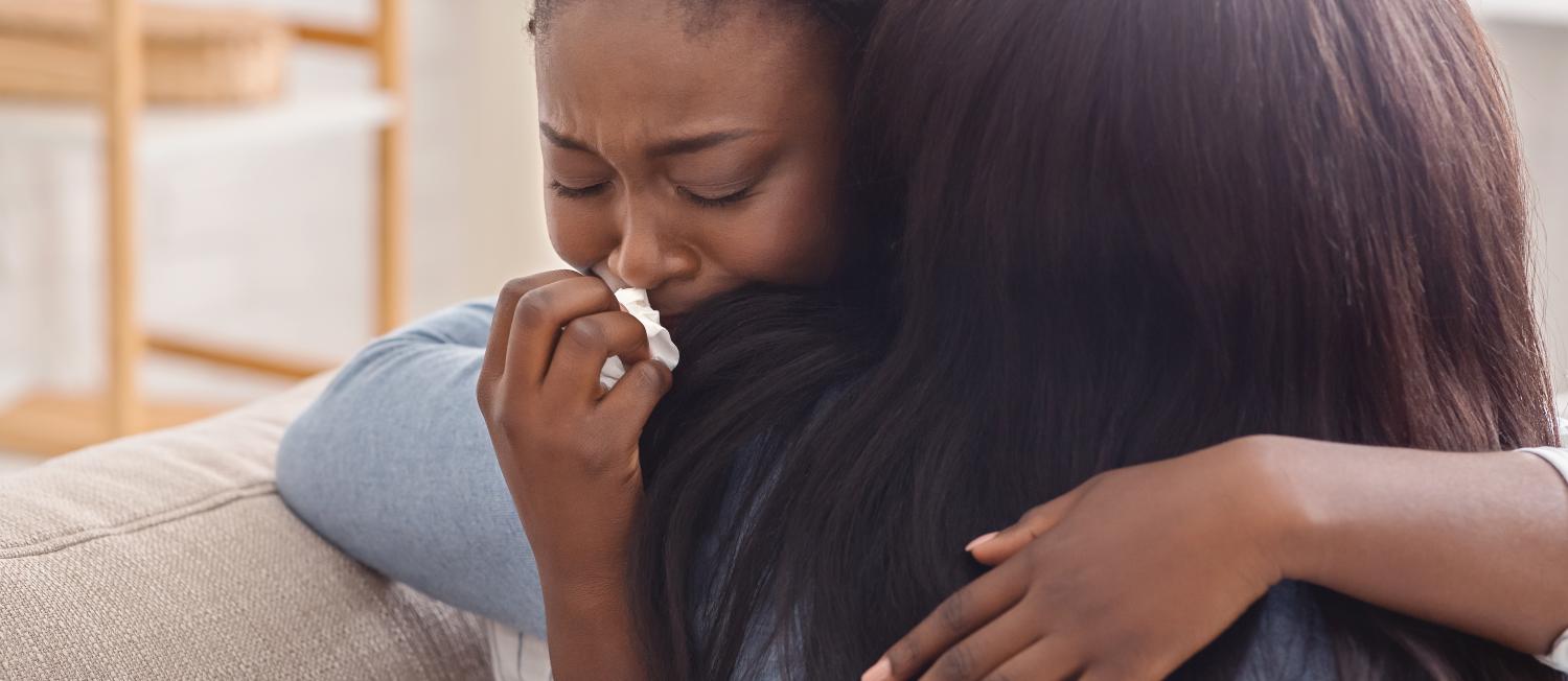 A woman embraces her tearful girlfriend, offering comfort and support after receiving difficult news.