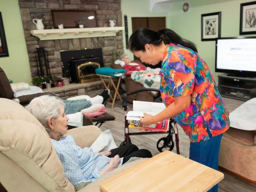 Caregiver helping with a book for a client.