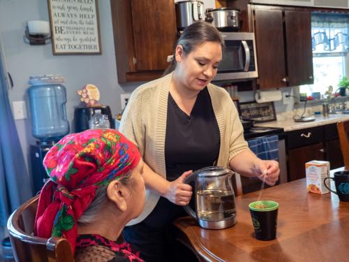 caregiver making tea for client at the kitchen table.