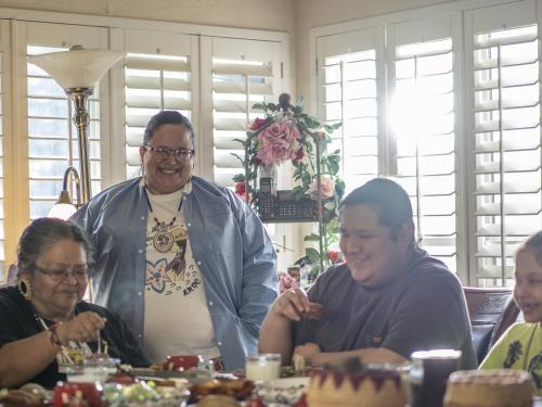 Indigenous Family sitting at a table eating and sharing in conversations.